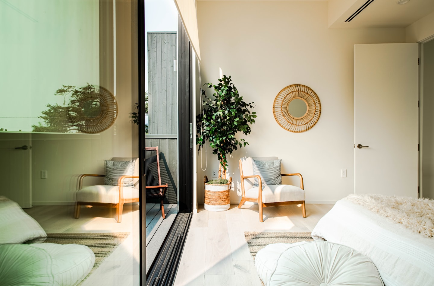 Sonnenlicht strömt in ein modernes Zimmer mit Sesseln und einem Bett.